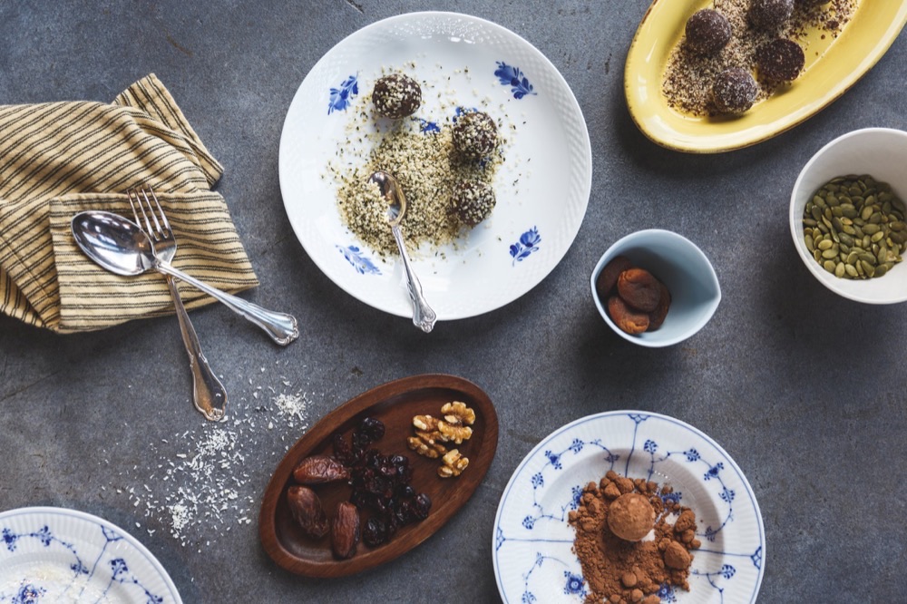 Bliss balls on a plate with cutlery, apricots, walnuts and pumpkin seeds